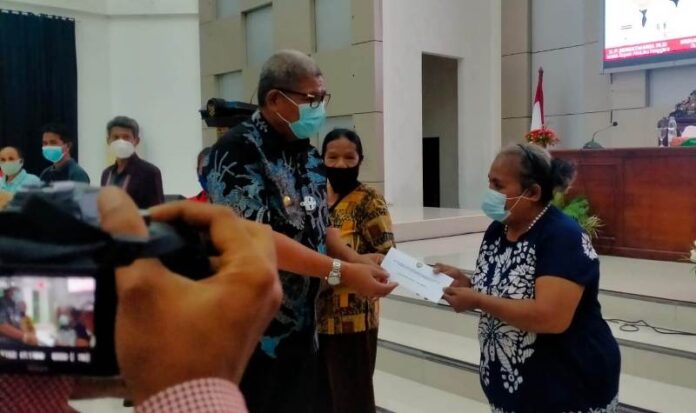 Bupati Maluku Tenggara M.Thaher Hanubun menyerahkan Bantuan Sosial Tunai (BST) secara simbolis kepada Sembilan perwakilan KPM di Aula Kantor Bupati, Kamis(9/12/2021). Foto: Labes Remetwa