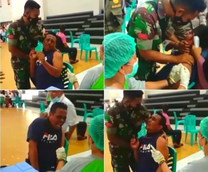 Seorang pria dengan postur tubuh besar yang belum diketahui identitasnya, terlihat histeris karena takut disuntik vaksin Covid-19 saat pelaksanaan vaksinasi di Gedung Serbaguna, Langgur, Maluku Tenggara, Rabu (12/1/2022). Foto: tangkapan layar